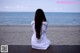 A woman sitting on a wooden dock looking out at the ocean.