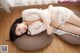 A woman in a white lingerie laying on a brown pillow.