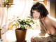 A woman sitting at a table next to a potted plant.