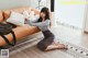 A woman sitting on the floor next to a couch.