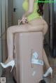 A woman sitting on top of a pink suitcase.